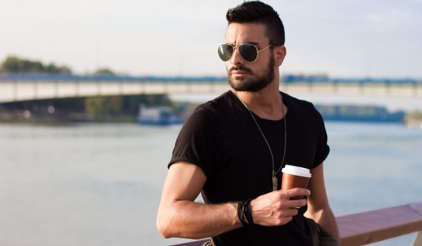 handsome man outdoors drinking coffee. with sunglasses, a guy with beard. instagram effect