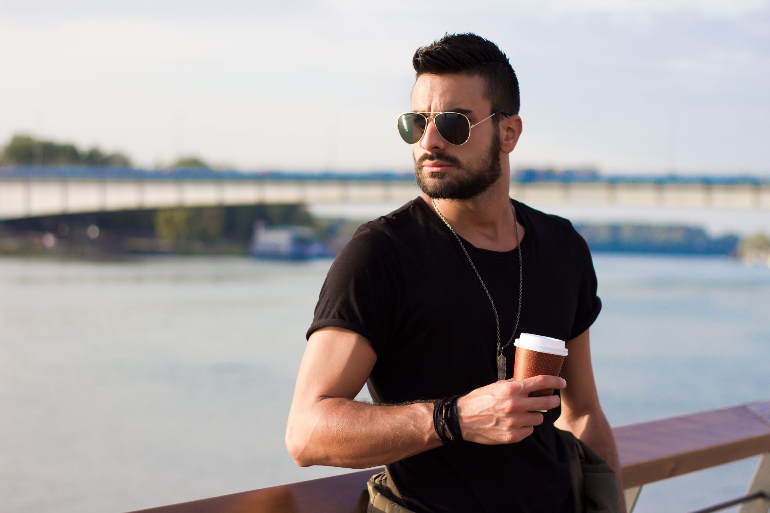 handsome man outdoors drinking coffee. with sunglasses, a guy with beard. instagram effect